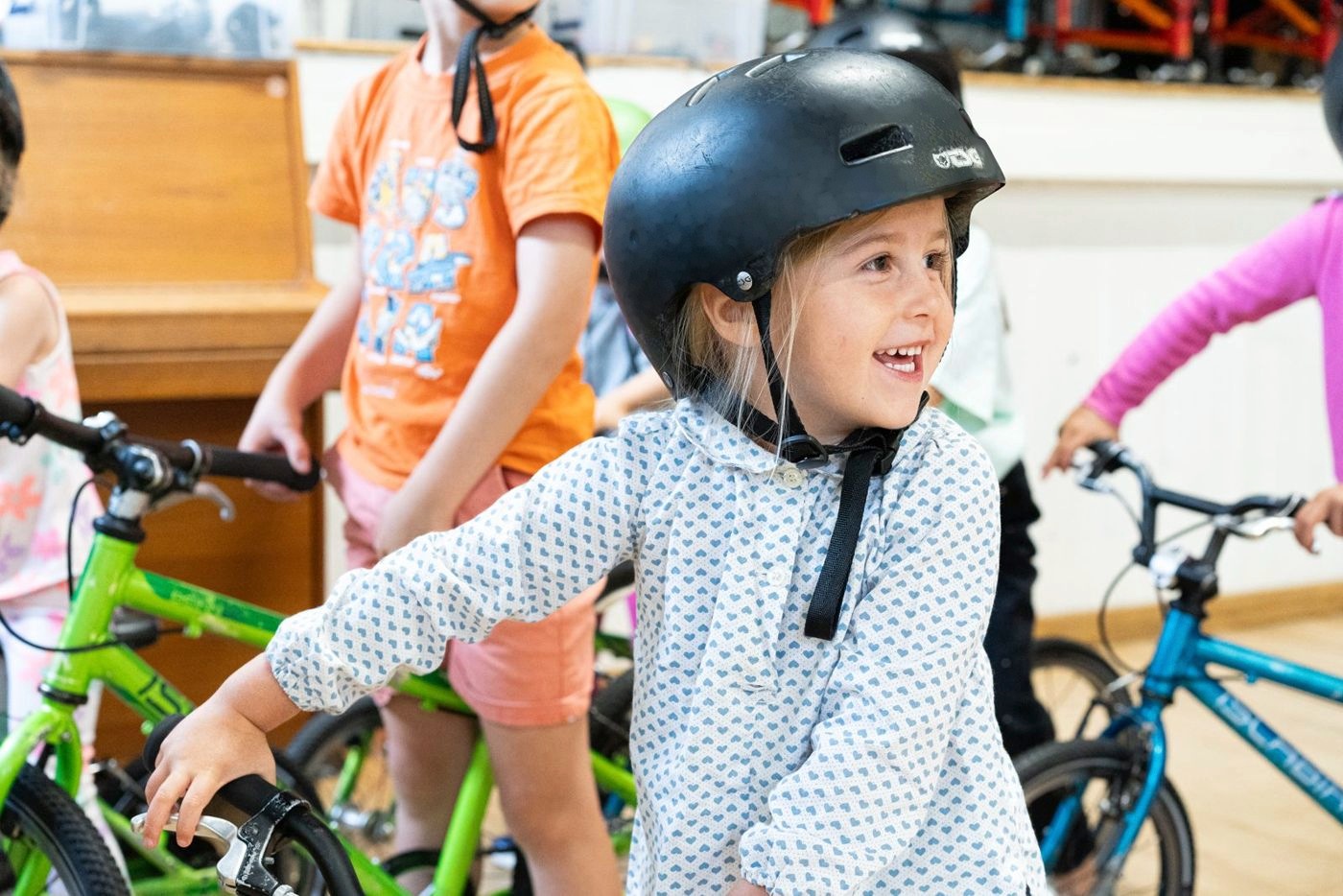 A smiling girl in a helmet on her bike at a Pedal Project course