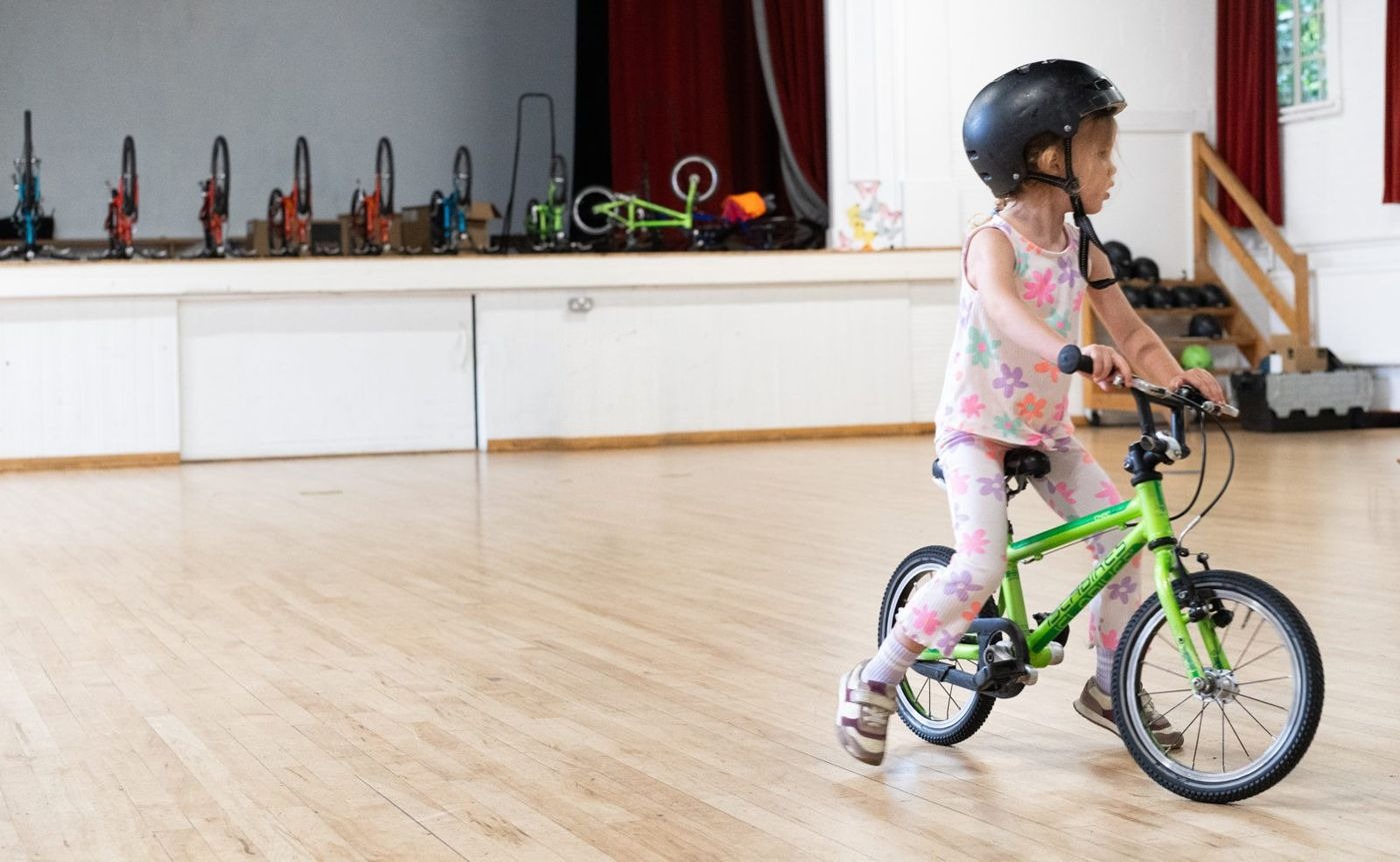 A girl cycling on a green bike